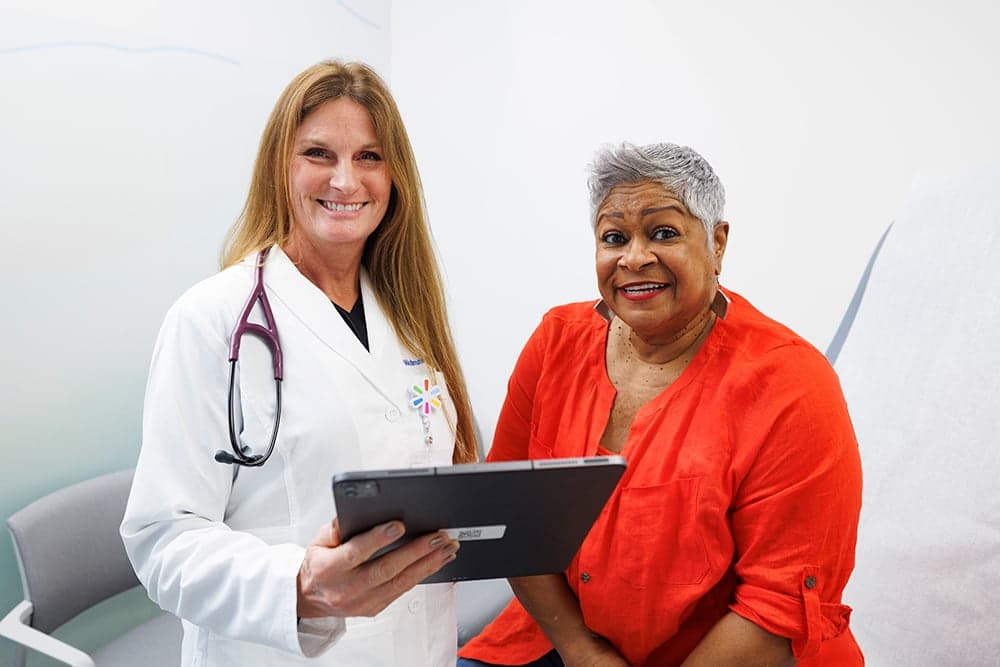 Image showing a smiling female patient and a doctor holding a tablet