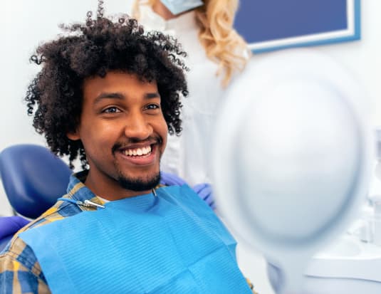 Young gentleman sitting in dental chair smiling